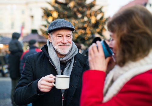 Senior couple on an outdoor Christmas market. Happy senior couple on an outdoor Christmas market, drinking tea or coffee. Winter time.